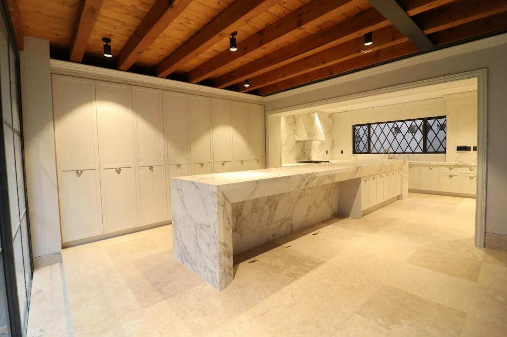Cocina con isla de mármol y techo de madera
